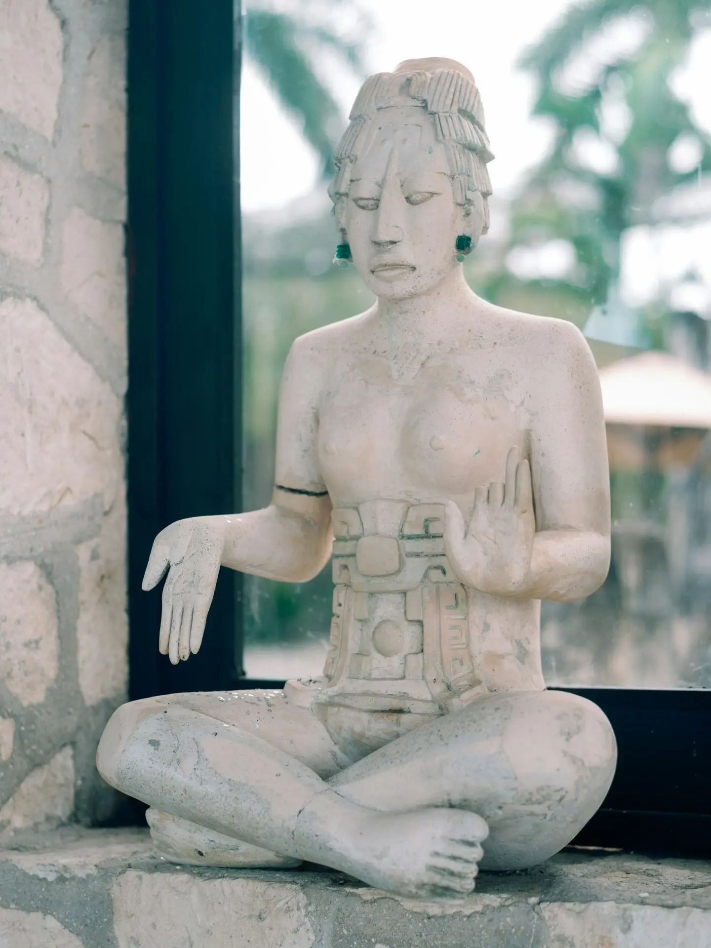 A statue of a person sitting on a window sill